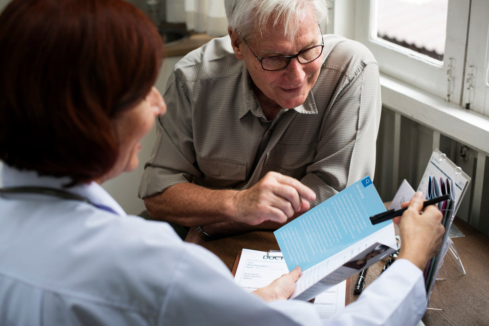 Healthcare professional reviewing informational documents with an older adult during a meeting about essential tremor resources.