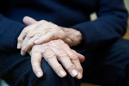 Close-up of elderly man's hands showing symptoms of Parkinson's disease.